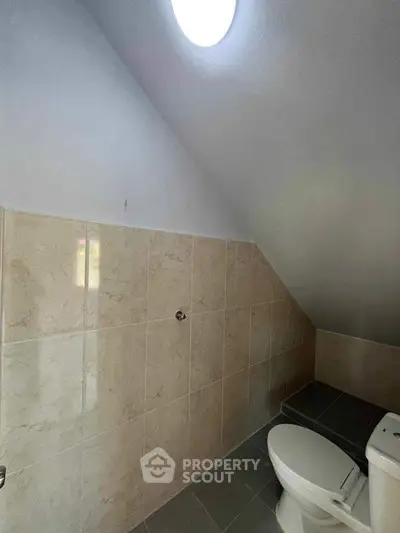 Compact bathroom with sloped ceiling and modern tile design