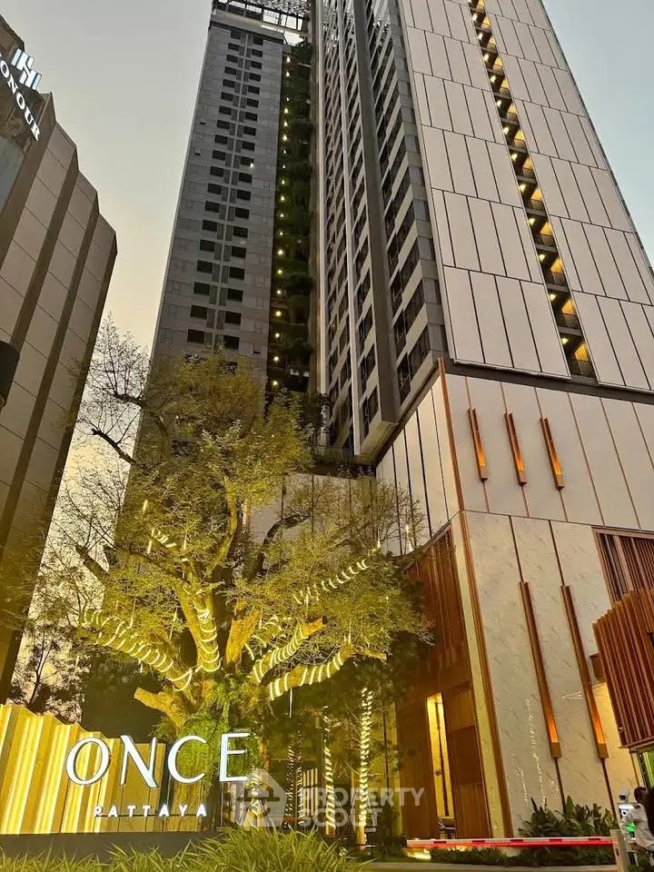 Stunning modern high-rise building with illuminated entrance in Pattaya, showcasing luxury urban living.