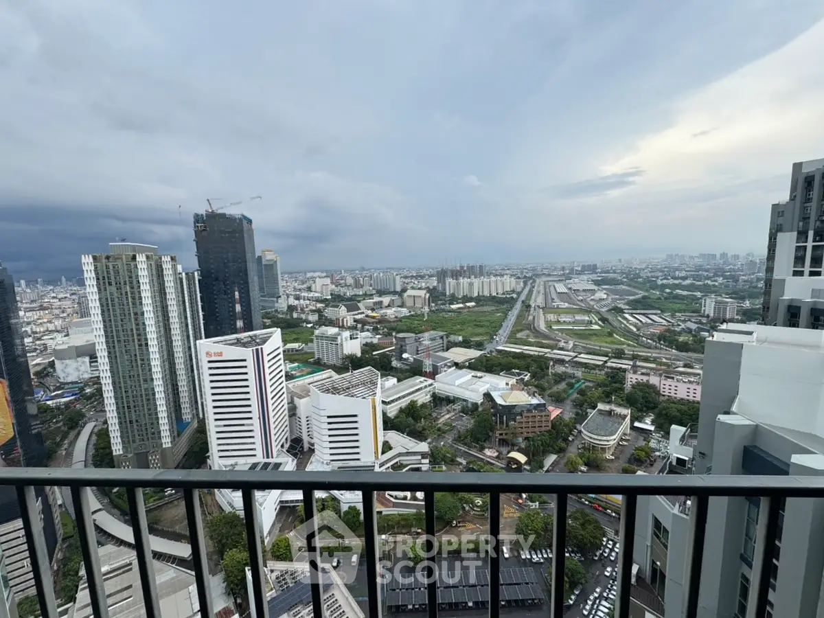 Stunning cityscape view from high-rise balcony overlooking urban skyline and railway tracks.