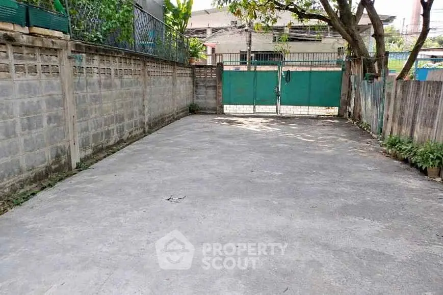 Spacious outdoor parking area with secure gated entrance and surrounding walls.
