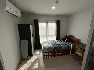Cozy bedroom with natural light, featuring a bed, wardrobe, and air conditioning.