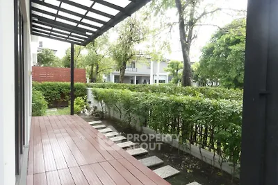 Charming garden view from a modern balcony with wooden decking and lush greenery.