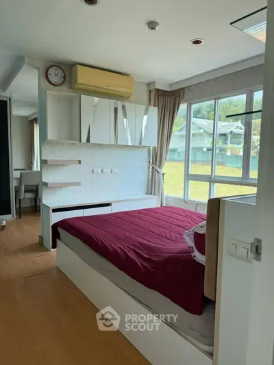 Bright bedroom with large windows and modern decor, offering a serene view of the outdoors.