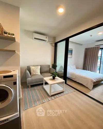 Modern apartment with cozy living room and bedroom, featuring a washing machine and stylish decor.