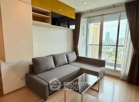 Modern living room with city view, featuring a sleek gray sofa and glass coffee table.