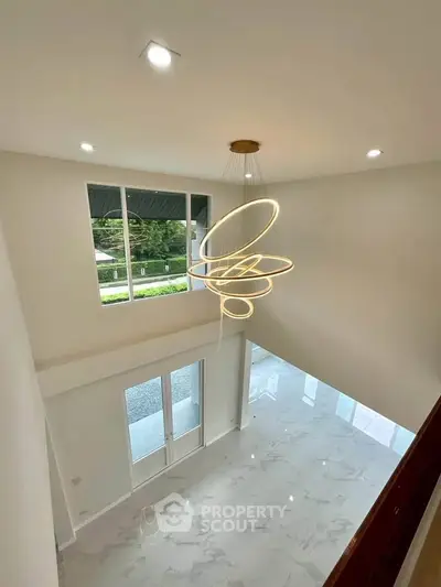 Stunning modern living room with high ceilings and elegant chandelier, featuring large windows for natural light.