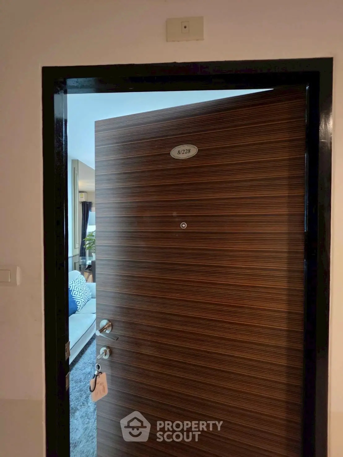 Modern apartment entrance with partially open wooden door revealing stylish interior.