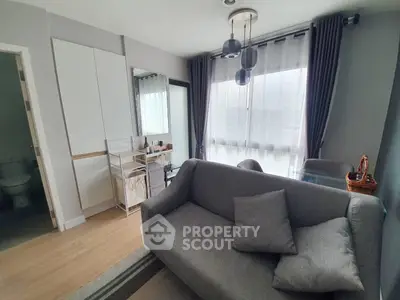 Modern living room with gray sofa, dining table, and large windows for natural light.