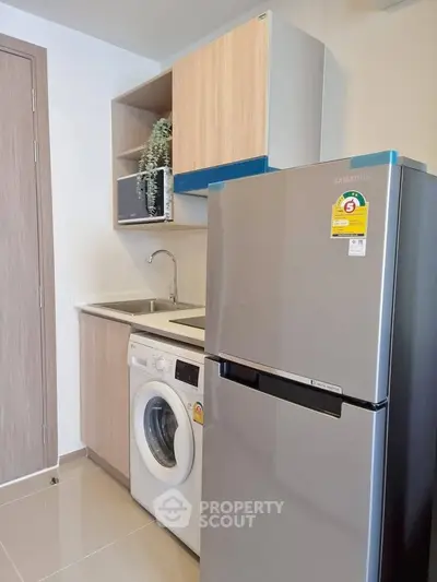 Modern kitchen with washing machine and fridge in compact layout