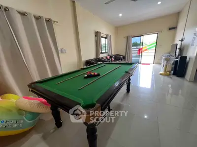 Spacious living room with pool table and balcony access, perfect for entertainment and relaxation.