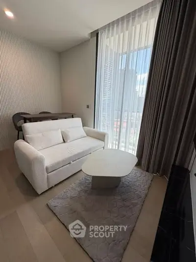 Modern living room with elegant sofa, stylish coffee table, and floor-to-ceiling windows offering city views.