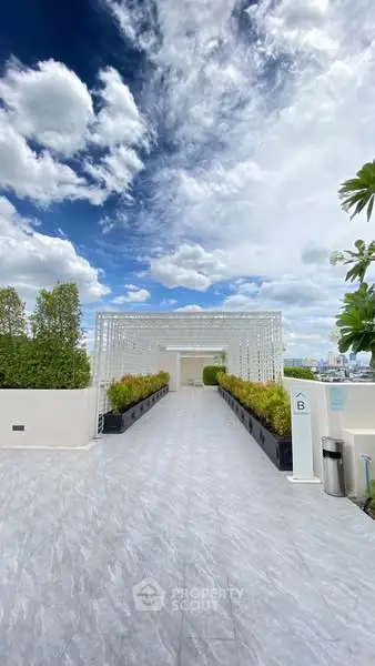 Stunning rooftop terrace with modern design and lush greenery under a vibrant sky.