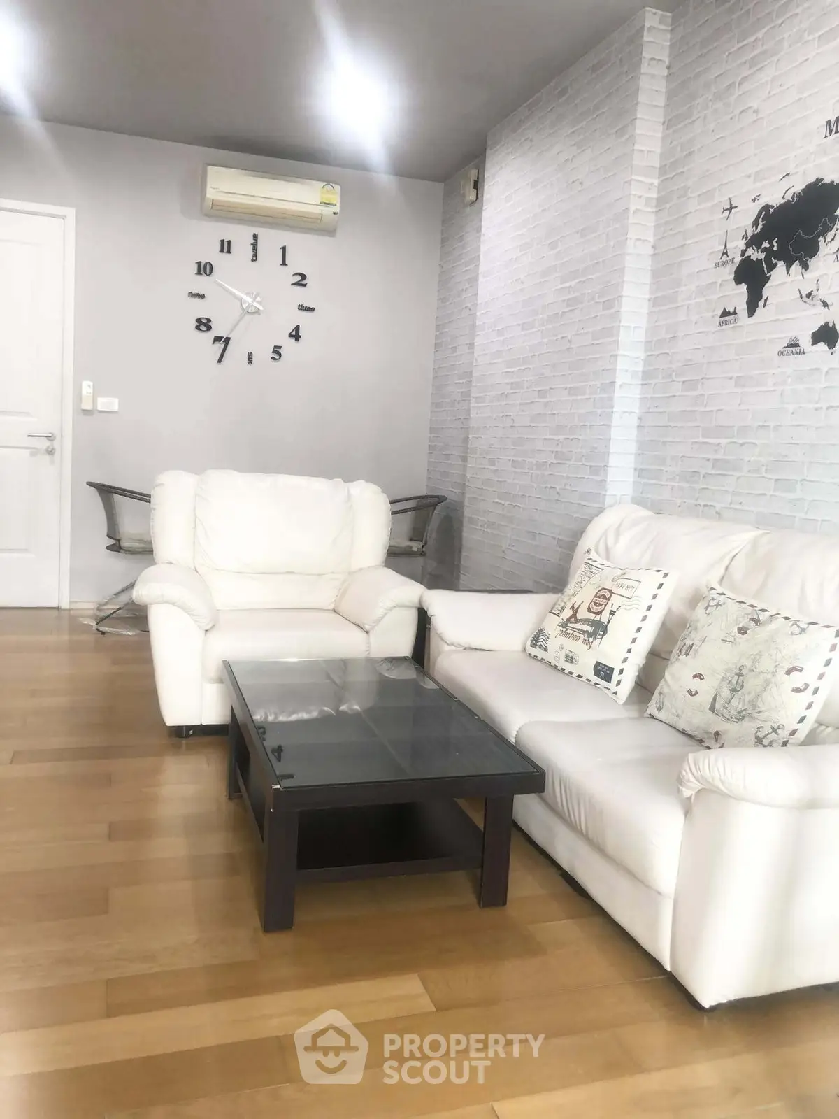 Modern living room with white sofas, wall clock, and stylish decor