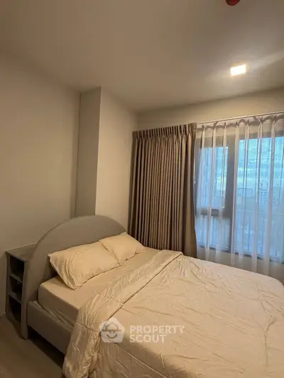 Cozy bedroom with modern decor and large window offering natural light.