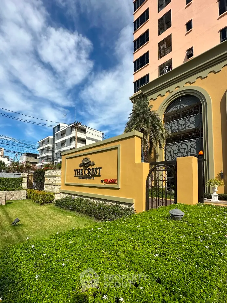 Elegant exterior view of The Crest condominium with lush greenery and clear blue sky.