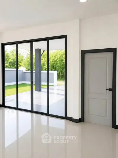 Modern interior with large glass doors opening to a patio and garden view, featuring sleek design and natural light.