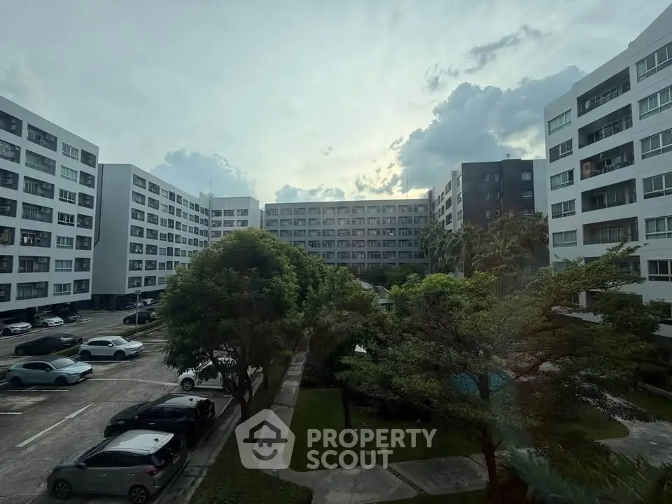 Modern apartment complex with lush greenery and ample parking space, offering a serene urban living experience.