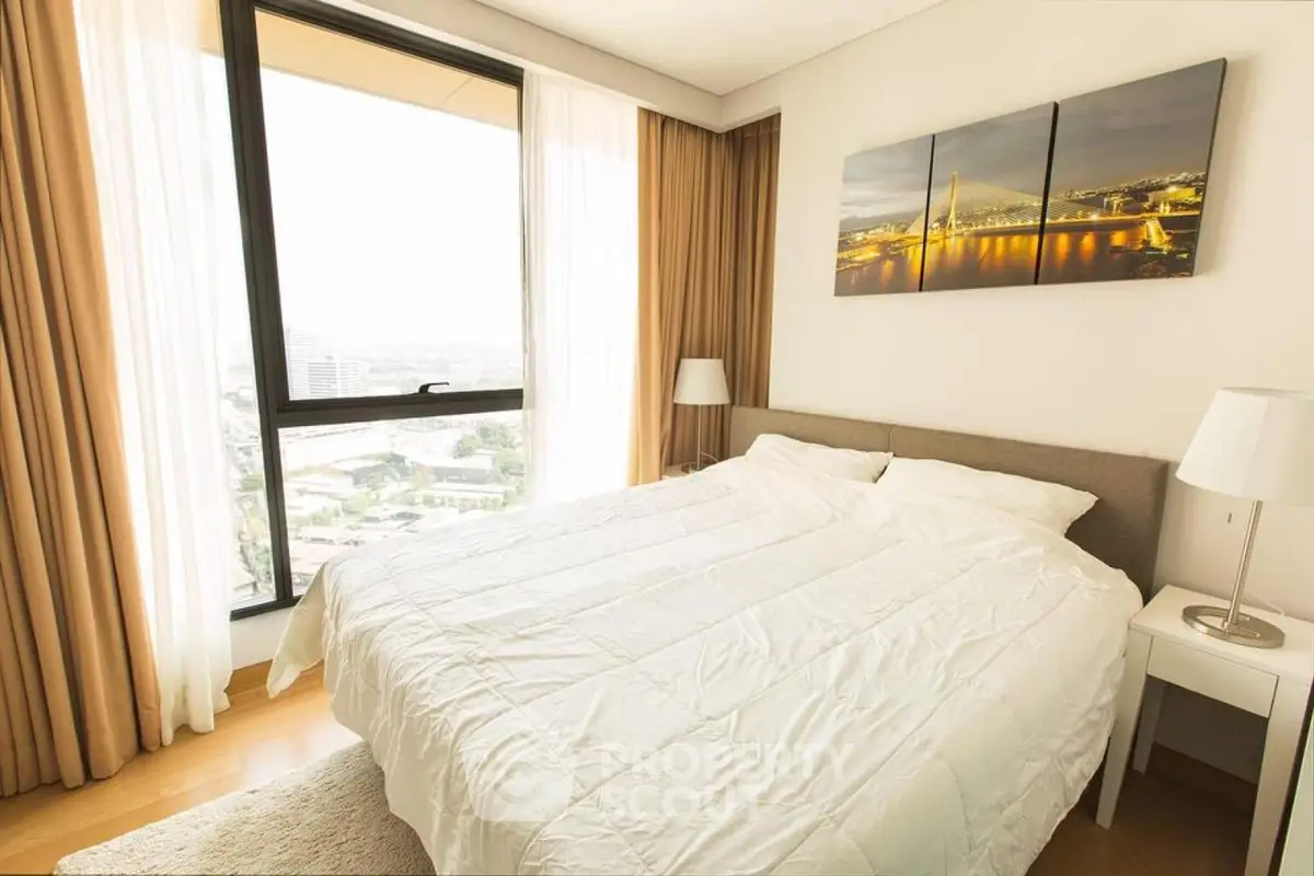 Bright and cozy bedroom with large window offering stunning city views, perfect for relaxation.