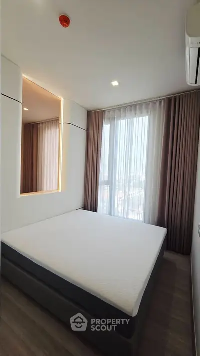 Modern bedroom with large window and stylish decor in a high-rise apartment.