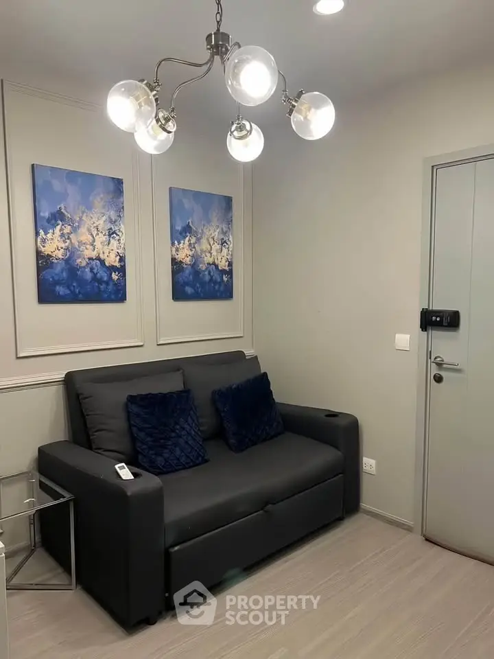 Modern living room with stylish gray sofa, elegant lighting, and abstract wall art, perfect for cozy relaxation.