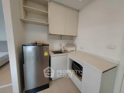 Modern compact kitchen with stainless steel fridge and sleek cabinetry