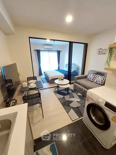Modern studio apartment with open layout, featuring a cozy living area and bedroom, plus in-unit washing machine.
