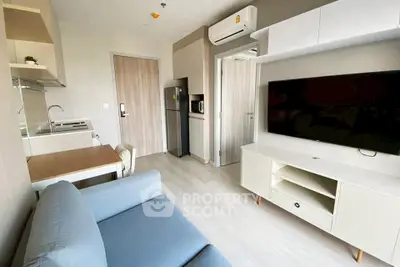 Modern living room with sleek furniture and compact kitchen in open layout apartment.