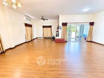 Spacious living room with wooden flooring and large windows for natural light.