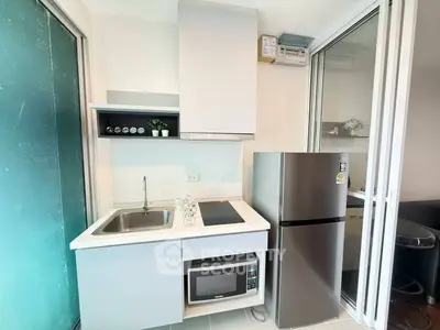 Modern compact kitchen with stainless steel fridge and microwave in sleek apartment
