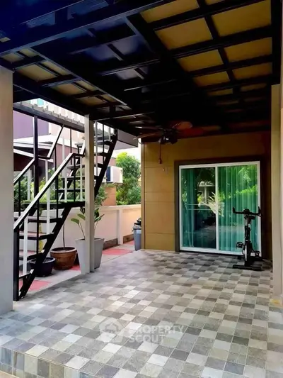 Modern covered patio with tiled flooring and staircase, ideal for outdoor relaxation and exercise.