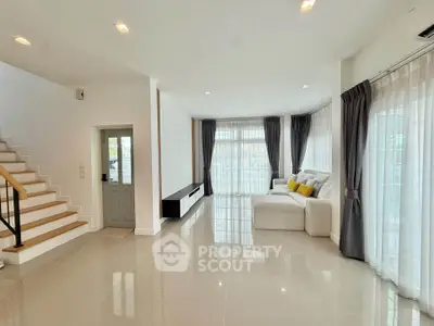Spacious modern living room with large windows and elegant staircase