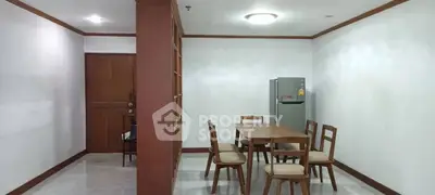 Spacious dining area with wooden furniture and modern fridge in a cozy apartment.