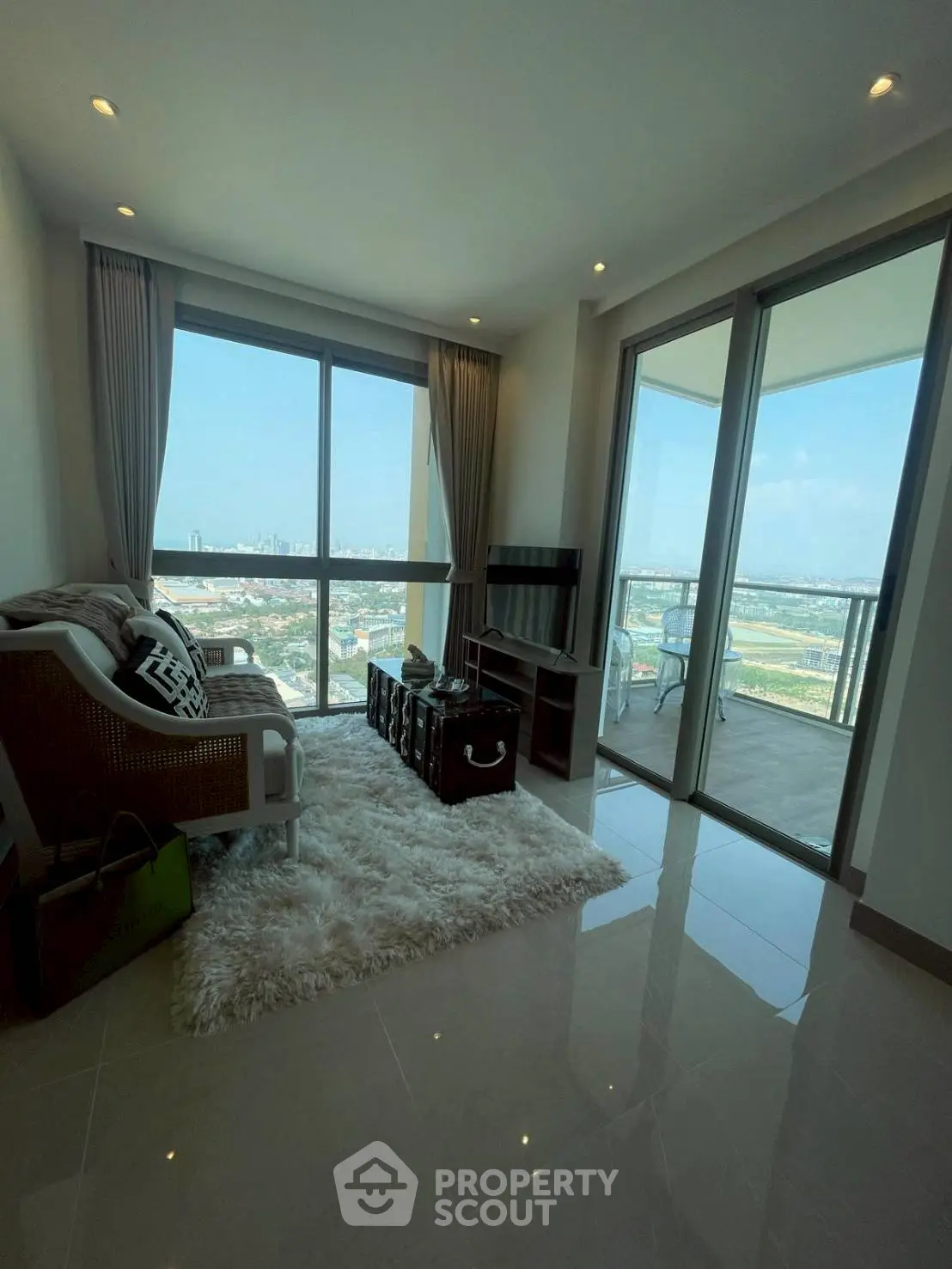 Modern living room with large windows and balcony offering stunning city views