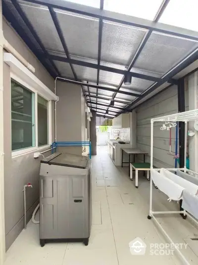 Modern laundry area with washing machine and drying rack in a sleek outdoor space.