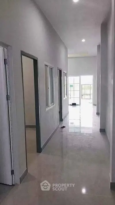 Spacious modern hallway with glossy floors leading to bright living area and balcony.