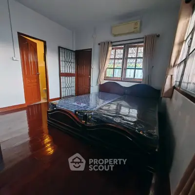 Cozy bedroom with wooden flooring and large windows for natural light.