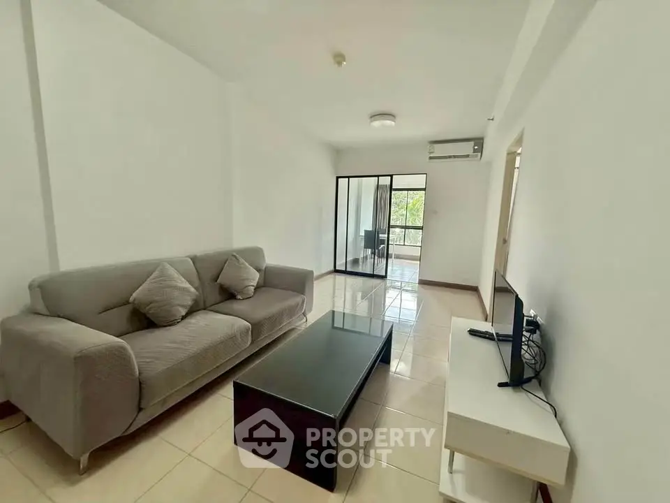 Spacious living room with modern sofa and TV, featuring a bright and airy ambiance.