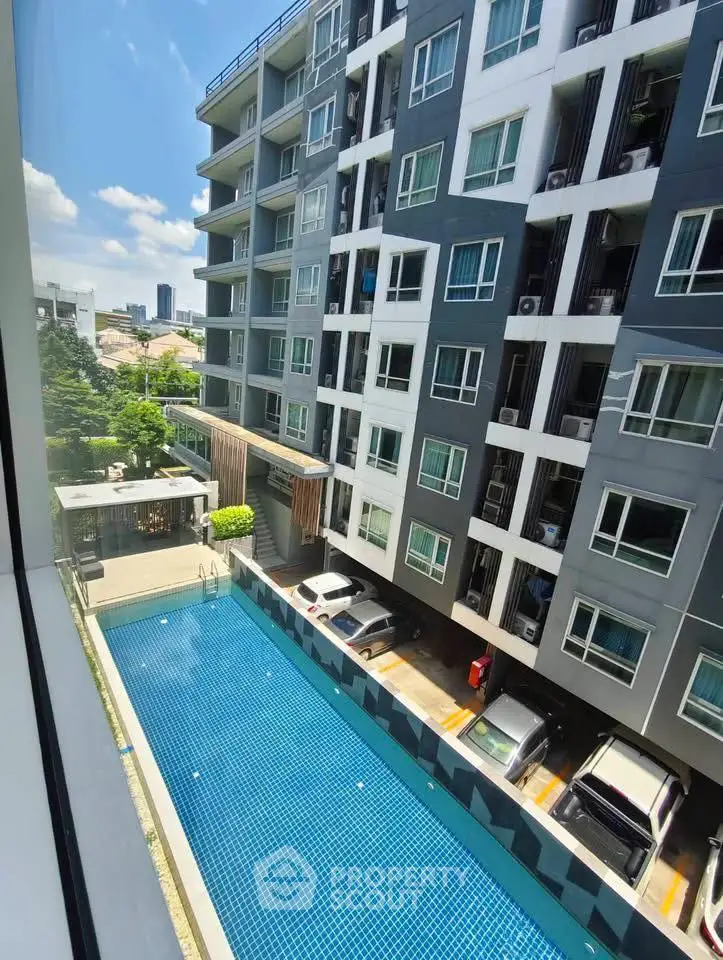 Modern apartment building with a swimming pool and city view, perfect for urban living.