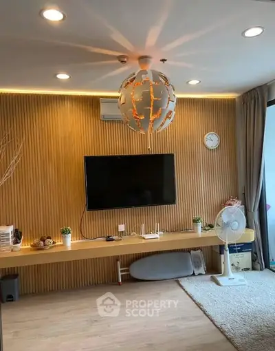 Modern living room with stylish lighting and wall-mounted TV, featuring wooden paneling and cozy decor.