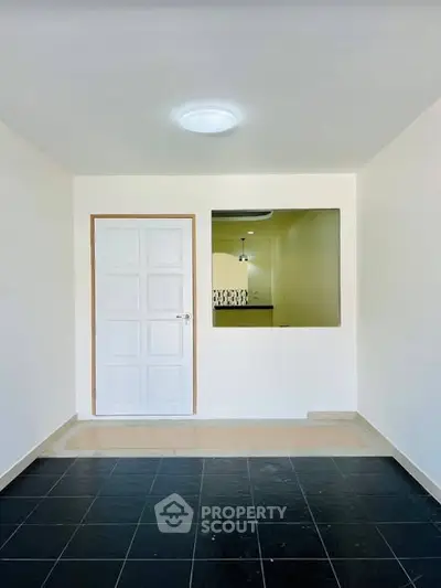 Modern minimalist interior with sleek black tile flooring and white door