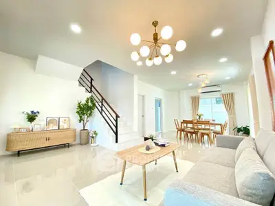 Spacious modern living room with elegant decor and dining area, featuring stylish lighting and open layout.