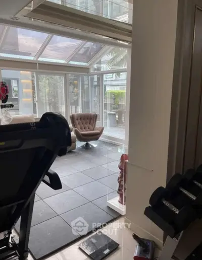 Modern home gym with glass walls and stylish seating area