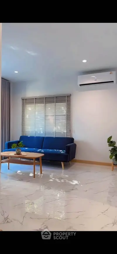 Modern living room with blue sofa, marble floor, and air conditioning unit.