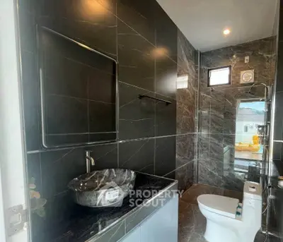 Luxurious modern bathroom with sleek black marble tiles and stylish fixtures.