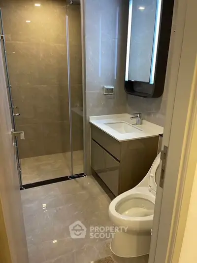 Modern bathroom with sleek fixtures and glass shower in luxury apartment.