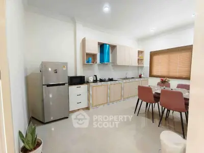 Modern kitchen with sleek appliances and dining area, featuring a gas stove and stylish decor.