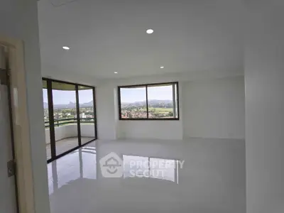 Spacious living room with large windows and stunning mountain views, featuring a sleek open layout and glossy floors.