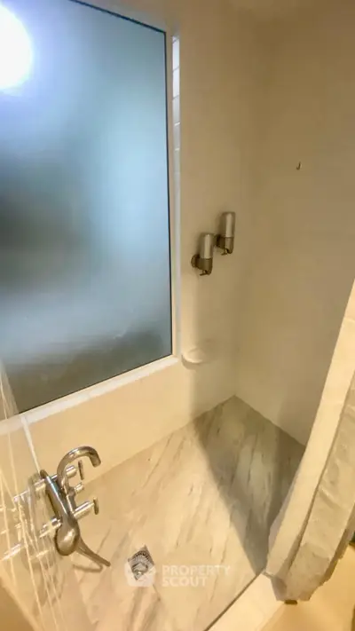 Modern bathroom with marble flooring and frosted glass window