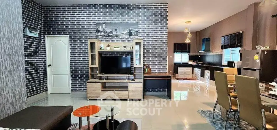 Modern open-plan living room with stylish brick accent wall and sleek kitchen area.