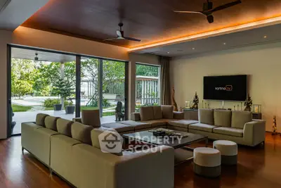 Luxurious living room with modern decor and pool view, featuring spacious seating and elegant lighting.